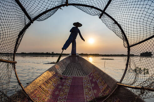 Myanmar, Shan-Staat, Silhouette eines traditionellen Intha-Fischers auf einem Boot auf dem Inle-See bei Sonnenuntergang - RUNF03922