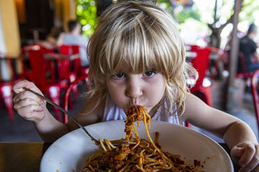 Girl eating spaghetti at restaurant - RUNF03926
