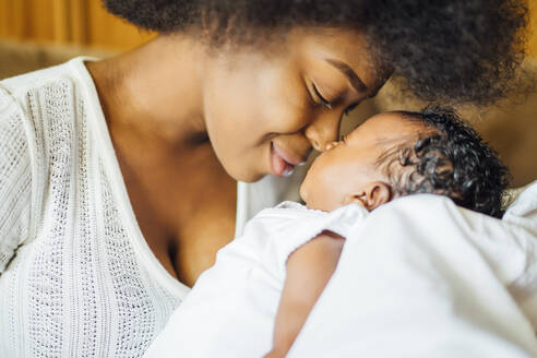 Close-up of mother rubbing noses with newborn daughter at home - OCMF01532