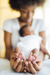 Nahaufnahme einer Mutter, die ihre neugeborene Tochter zu Hause im Bett trägt - OCMF01537