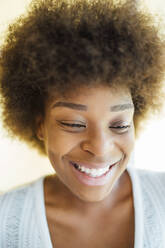 Nahaufnahme einer lächelnden Frau mit Afro-Haar, die auf ihr Haus hinunterblickt - OCMF01543