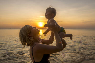 Vietnam, Phu Quoc Insel, Ong Lang Strand, Mutter hält Baby am Strand bei Sonnenuntergang - RUNF03945