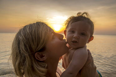 Vietnam, Phu Quoc Insel, Ong Lang Strand, Mutter küsst Baby am Strand bei Sonnenuntergang - RUNF03946