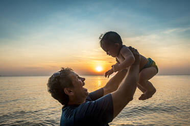 Vietnam, Phu Quoc Insel, Ong Lang Strand, Vater hält Baby am Strand bei Sonnenuntergang - RUNF03947