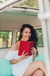 Frau sitzt in einem Wohnwagen und liest ein Buch - ADSF04150