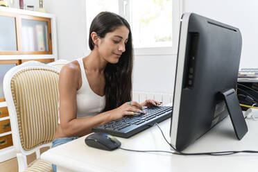 Mittlere erwachsene Frau, die einen Computer auf einem Schreibtisch im Heimbüro benutzt - EGAF00519