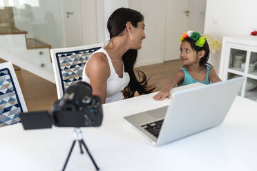 Mutter spricht mit Tochter, während sie zu Hause auf dem Tisch ein Video aufnimmt - EGAF00539
