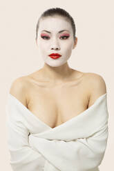 Junge Frau mit Opernschminke in Decke eingewickelt vor weißem Hintergrund - EAF00025