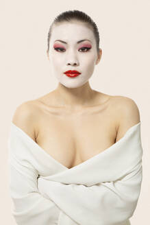 Young woman with opera make-up wrapped in blanket against white background - EAF00025