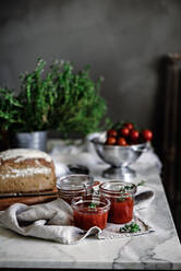 Köstliche frische aromatische Roggenbrot auf Serviette neben Messer und Dosen mit Tomaten hausgemachte Marmelade auf unscharfen Hintergrund - ADSF04275