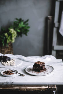 Leckeres süßes veganes Brownie-Dessert und Kakaopulver auf einem Teller auf einem Tisch. - ADSF04281