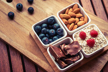 Small square bowls with various food for delicious breakfast standing on wooden board - ADSF04375