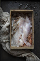 Ansicht von rohem Fisch und verschiedenen Meeresfrüchten in Eis in einer Holzkiste. - ADSF04396