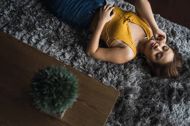 Woman with earphones lying on floor - ADSF04409