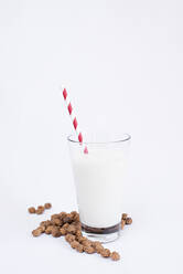 Haufen von leckeren Rosinen liegen in der Nähe Glas mit frischer Milch und gestreiften Stroh auf weißem Hintergrund - ADSF04446