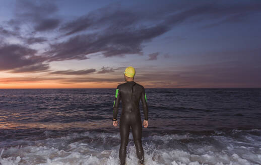 Triathlet beim Training für den Ironman auf See mit seinem Neoprenanzug an einem Frühlingsmorgen - ADSF04499