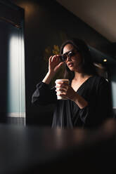 Woman in sunglasses having coffee - ADSF04555