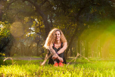 Glückliche Frau auf sonnigem Rasen sitzend - ADSF04621
