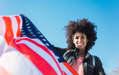 Schwarze Frau mit Afro-Haar und einer amerikanischen Flagge feiert den Unabhängigkeitstag der USA - ADSF04688