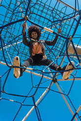 Woman with afro hair climbing by children's attractions in a park - ADSF04696