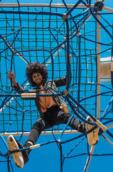 Woman with afro hair climbing by children's attractions in a park - ADSF04697