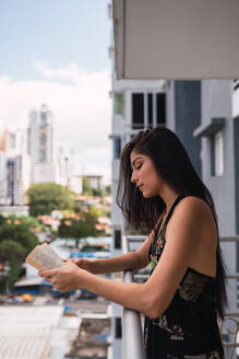 Schöne leidenschaftliche brunette Frau im Kleid Volumen auf Balkon in der Nähe von modernen Gebäuden - ADSF04821