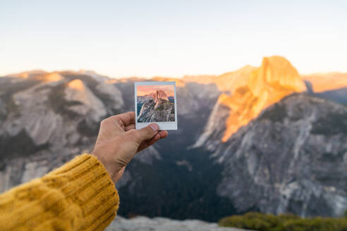 Crop Hand des Menschen hält Schuss und malerischen Blick auf die Berge bei Sonnenaufgang in Yosemite - ADSF04843