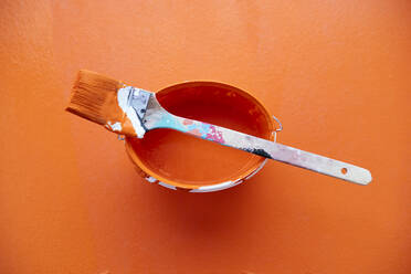 Studio shot of paintbrush on top of bucket with orange paint - PPXF00307