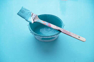 Studio shot of paintbrush on top of bucket with turquoise paint - PPXF00308