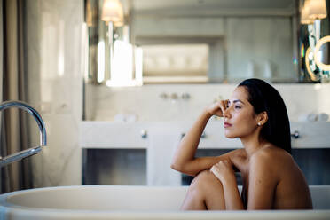 Woman relaxing in bathtub in suite - CUF56123