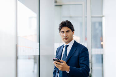 Businessman using smartphone in office building - CUF56133