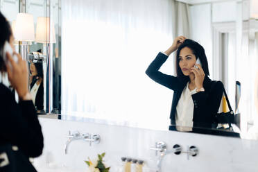 Geschäftsfrau benutzt Smartphone im Badezimmer einer Suite - CUF56138