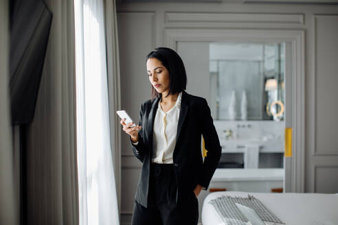 Geschäftsfrau benutzt Smartphone in Suite - CUF56139