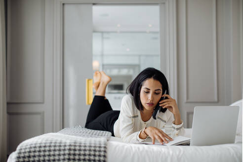 Geschäftsfrau mit Smartphone und Laptop in einer Suite - CUF56140