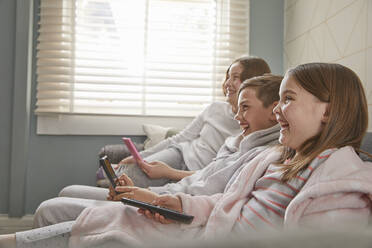 Group of children sitting on a sofa in their pajamas, watching television. - CUF56157