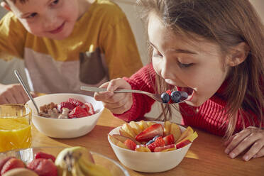 Boy and girl sitting at kitchen table, eating breakfast. - CUF56160