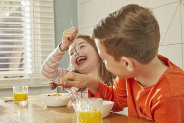 Boy and girl sitting at kitchen table, eating breakfast. - CUF56161