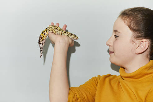 Close up of teenage girl holding spotted pet leopard gecko. - CUF56165