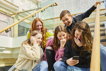 Gruppe von Teenagermädchen in einem Einkaufszentrum, die ihre Handys überprüfen. - CUF56169