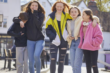 Gruppe von Mädchen und Jungen im Teenageralter, die Seite an Seite im Freien spazieren gehen. - CUF56172