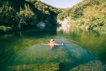 Rückenansicht von shirtless Kerl in Hut stehend in sauberem Wasser der erstaunlichen See in den Bergen - ADSF04846