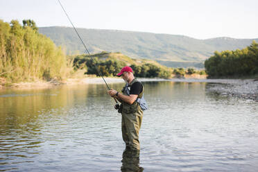 Mann steht im Wasser und fischt - ADSF04868