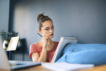 Geschäftsfrau mit Notizblock und Bleistift, die sich am Schreibtisch im Heimbüro ausruht - BSZF01586