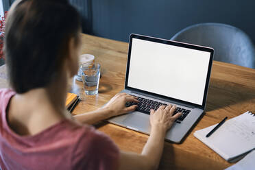 Female freelancer using laptop on desk in home office - BSZF01591