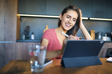 Lächelnde Geschäftsfrau, die ein digitales Tablet auf dem Schreibtisch im Heimbüro benutzt - BSZF01603