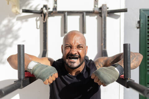 Close-up of bald mature man with mouthguard exercising against wall in yard stock photo