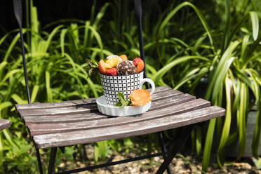 Dessert with energy balls (raw confectionery) and fresh fruits and flowers on garden chair - EVGF03644