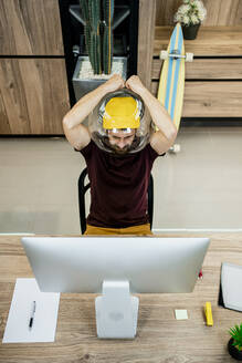 Angespannter Geschäftsmann trägt ein Fischglas, während er einen Computer in einem modernen Büro benutzt - RCPF00240