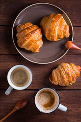 Von oben zwei Tassen Kaffee und Croissants auf einem Holztisch. - ADSF05278