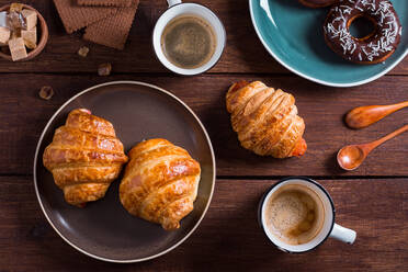 Von oben Hände einer nicht erkennbaren Person mit einer Tasse Kaffee und einem frischen Croissant. - ADSF05279